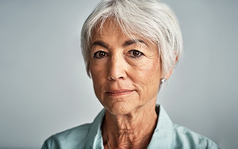An older woman looking directly into the camera with a straight face