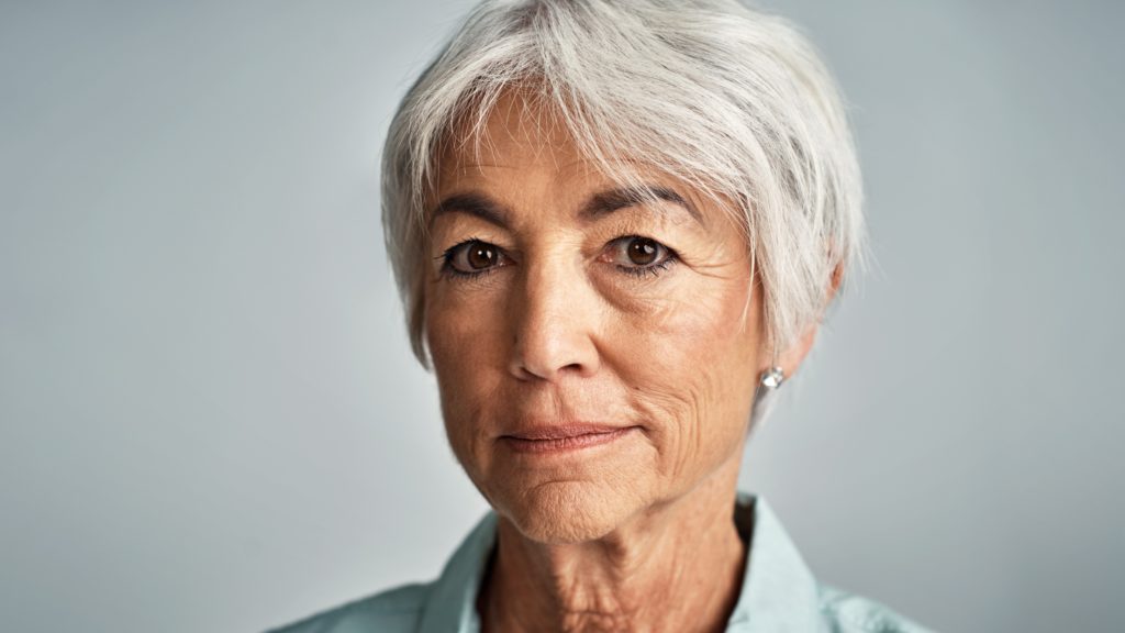 Studio portrait of a senior woman posing against a grey background